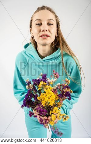 Unaltered Candid Emotional Portrait Of Young Happy Blonde Long Hair Woman With Flower Bouquet On Lig
