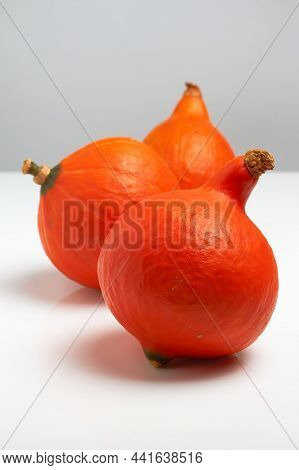Three Orange Small Pumpkins On A White Table