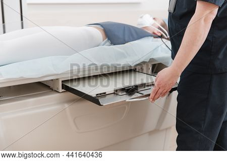 Doctor Taking X-ray Of Patient Lying On Gurney. Hospital Radiology Room. Technician Adjusting An X-r
