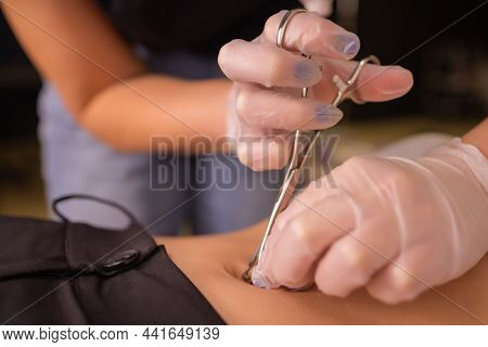 The First Piercing. Dressing The Earrings On The Navel. Female Piercing.