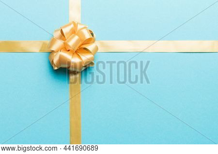 Top View Of Gold Ribbon Rolled And Yellowbow Isolated On Colored Background. Flat Lay With Copy Spac