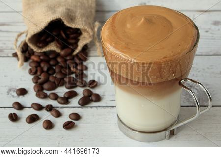Cup Of Dalgona Coffee On Wooden Table With Bag Of Natural Coffee Beans