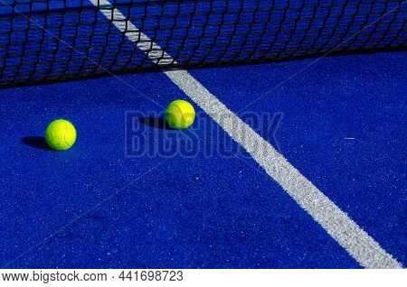Two Balls Next To The Net Of A Paddle Tennis Court. Racket Sport Concept.