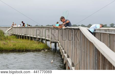 Assateague Island, Maryland, U.s.a - September 21, 2021 - A Man Crabbing Using A Line And A Net On T