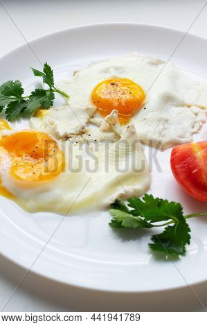 Two Fried Eggs With Tomatoes And Herbs On A White Plate. Ugly Food Concept. Vertial Orientation. Ugl