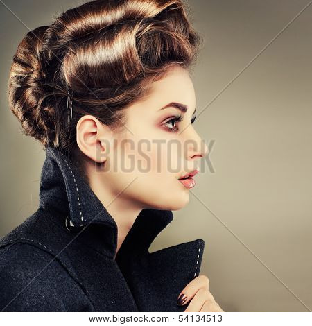 Portrait of elegant young woman in a grey overcoat  on a grey background