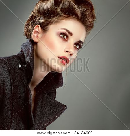 Portrait of elegant young woman in a grey overcoat  on a grey background