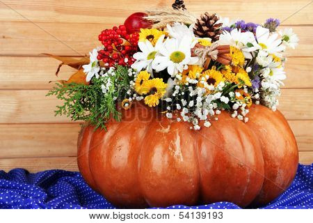 Beautiful autumn composition in pumpkin on table on wooden background