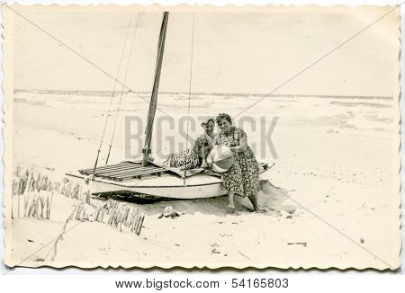 MIELNO,POLAND, CIRCA FIFTIES -  vintage photo of unidentified women resting on boat at the seaside  - in Mielno, Poland circa fifties