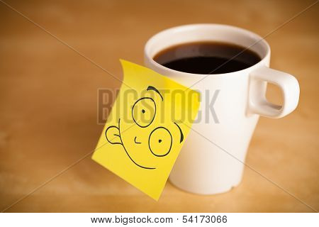Drawn smiley face on a post-it note sticked on a cup