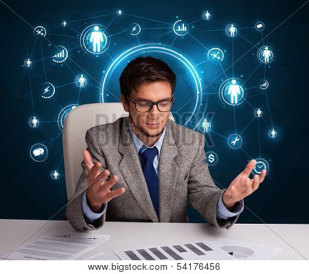 Young businessman sitting at desc with social network icons