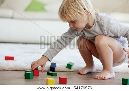 Toddler playing with wooden blocks at home