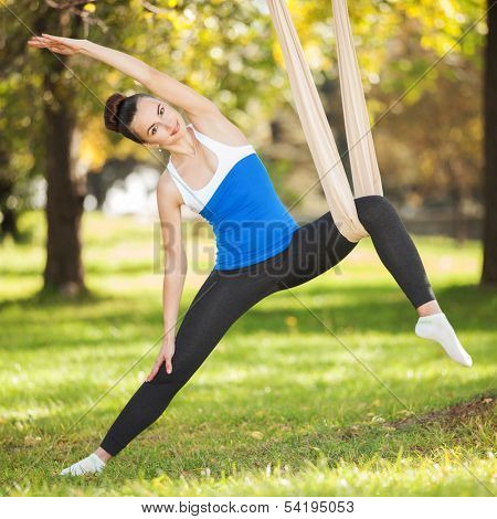 Anti-gravity Yoga, woman doing yoga exercises in the park
