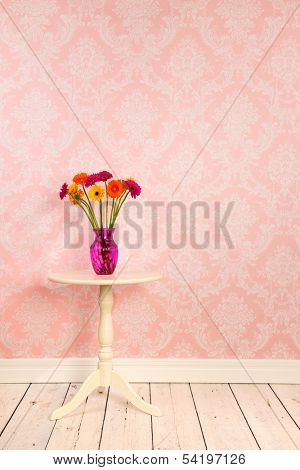Vintage wall, wooden floor and plinth with white table and vase with flowers