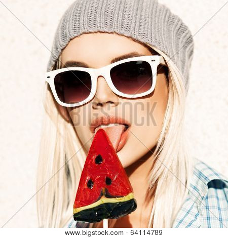 Beautiful Blonde Girl In Beanie Hat With Smokey Eye Make Up Who Enjoys Licking Watermelon Lolipop