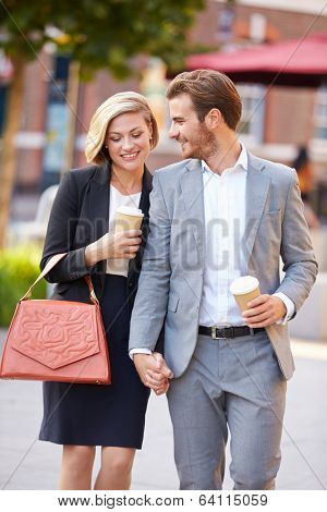 Business Couple Walking Through Park With Takeaway Coffee