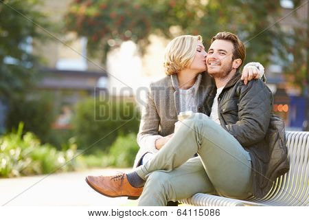 Couple Relaxing On Park Bench With Takeaway Coffee