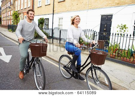 Couple Cycling Along Urban Street Together