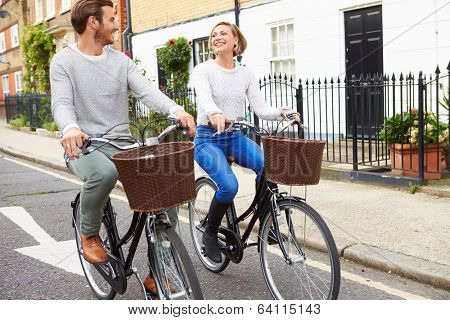 Couple Cycling Along Urban Street Together