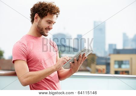 Man On Roof Terrace Using Digital Tablet