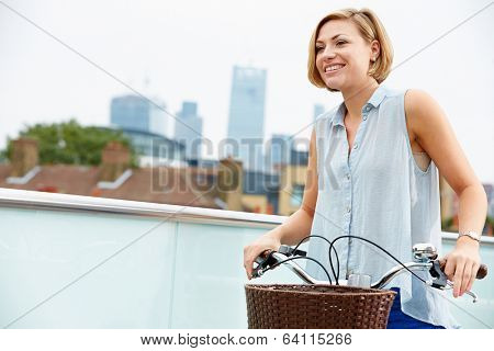 Woman Pushing Bike With City Skyline In Background