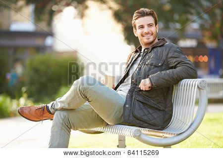 Man Relaxing On Park Bench With Takeaway Coffee