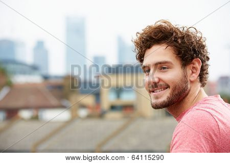 Young Man Looking Out Over City From Roof Terrace