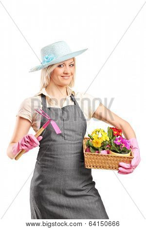 Female gardener holding a mattock and a basket with flowers isolated on white background