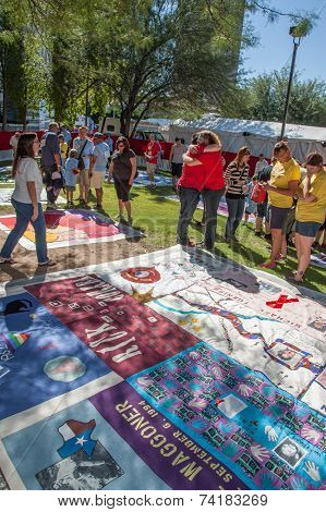 People Hugging Near Section Of Aids Quilt