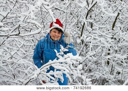 Woman In Ski Suit And Cap Of Santa Klaus  In Snow-covered Wood