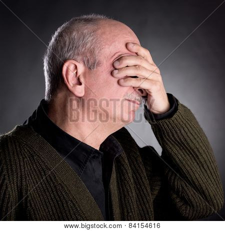 Elderly Man Covers His Face With Hand