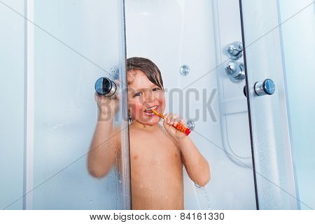 Little boy brush teeth with toothbrush in shower