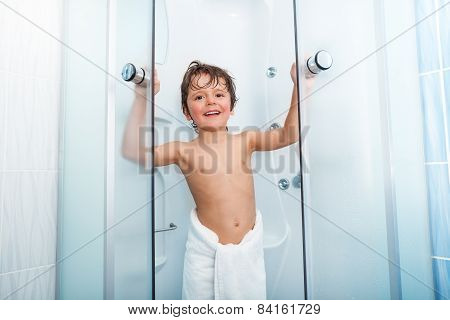 Happy boy getting out of shower covered in towel