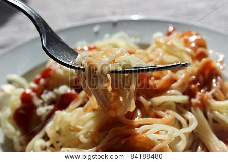 Spaghetti with ketchup and cheese on a plate.