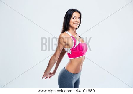 Happy fitness woman stretching hands over gray background. Looking at camera