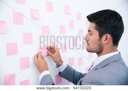 Businessman looking at sticker on wall in office