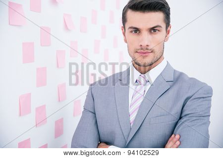 Handsome young businessman in suit standing in office and looking at camera