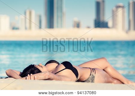 Sexy woman lying on Al Mamzar city beach, Dubai, close to the water