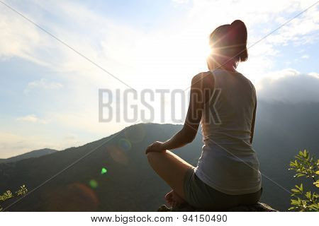 young yoga woman sit meditation on sunrise mountain peak rock