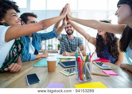 Creative business team putting hands together at the office