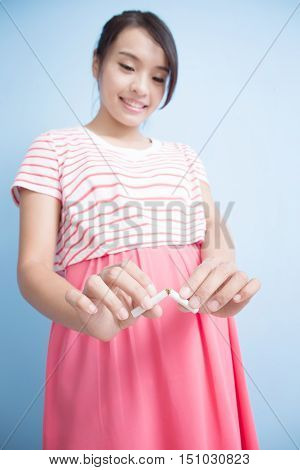 Quit smoking pregnant woman hands breaking the cigarette close upisolated on blue background