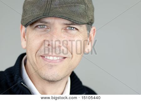Smiling Man In Newsboy Hat Looks To Camera