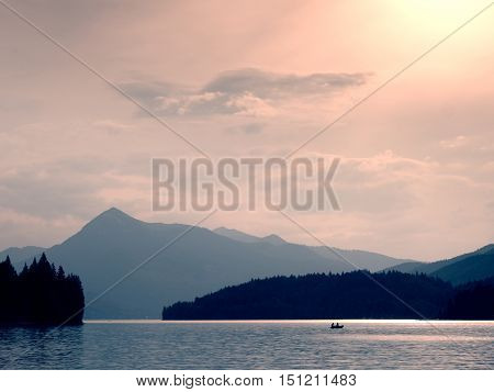 Abandoned Fishing Paddle Boat On Alps Lake. Evening Lake Glowing By Sunlight.