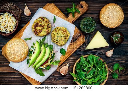 Zucchini quinoa veggie burger with pesto sauce and sprouts. Vegetarian burger on a cooking sheet ready to prepare hamburger. Top view overhead flat lay