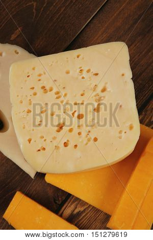 various types of fresh raw aged delicatessen cheese on wooden table cheddar edam swiss