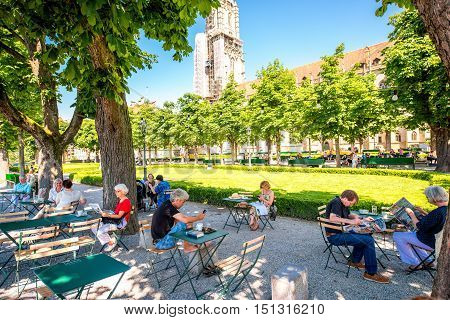 Bern, Switzerland - June 24, 2016: People sit at the outdoor cafe in the park near Munster church in the old town of Bern in Switzerland.
