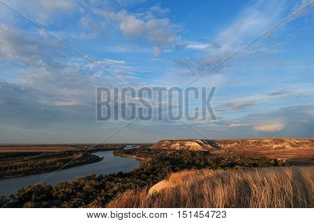 Golden sunset on the river. Autumn landscape. Beautiful clouds and hills.