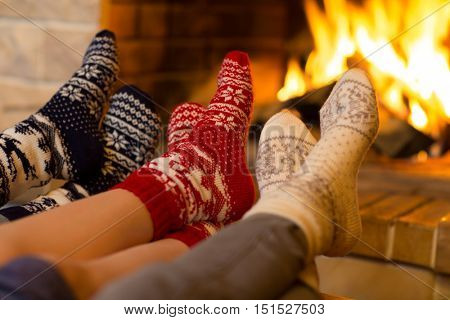 Family in socks near fireplace in winter or christmas time