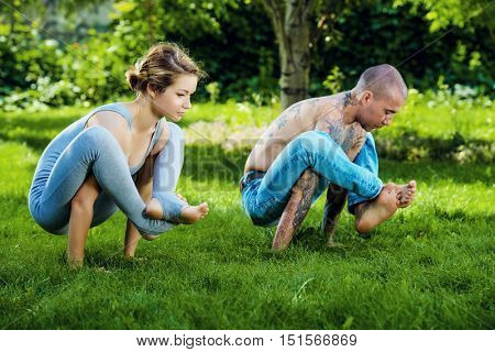 Man and woman yogi doing various yoga poses in a pair. Healthy yoga lifestyle. Yoga in the summer park, outdoor.