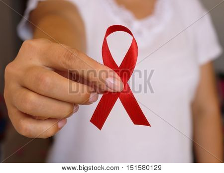 The symbolic conception of the world day of fight against AIDS. The red ribbon in the hands of a young woman.